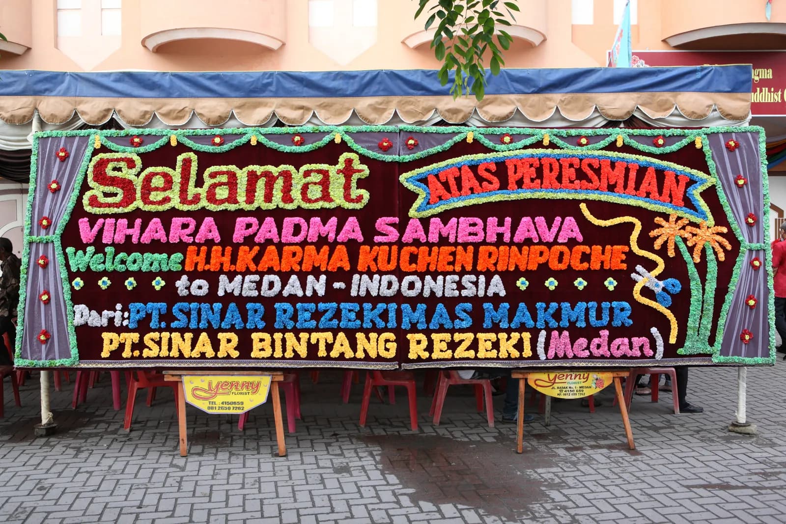 Papan bunga ucapan selamat dari umat dan donatur yang berdiri di halaman vihara pada hari peresmian.